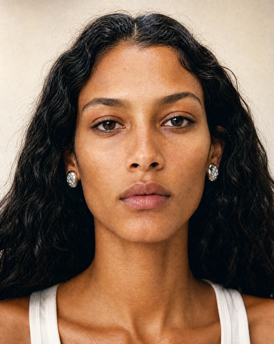 A close-up portrait of a woman wearing The Swell Studs earrings