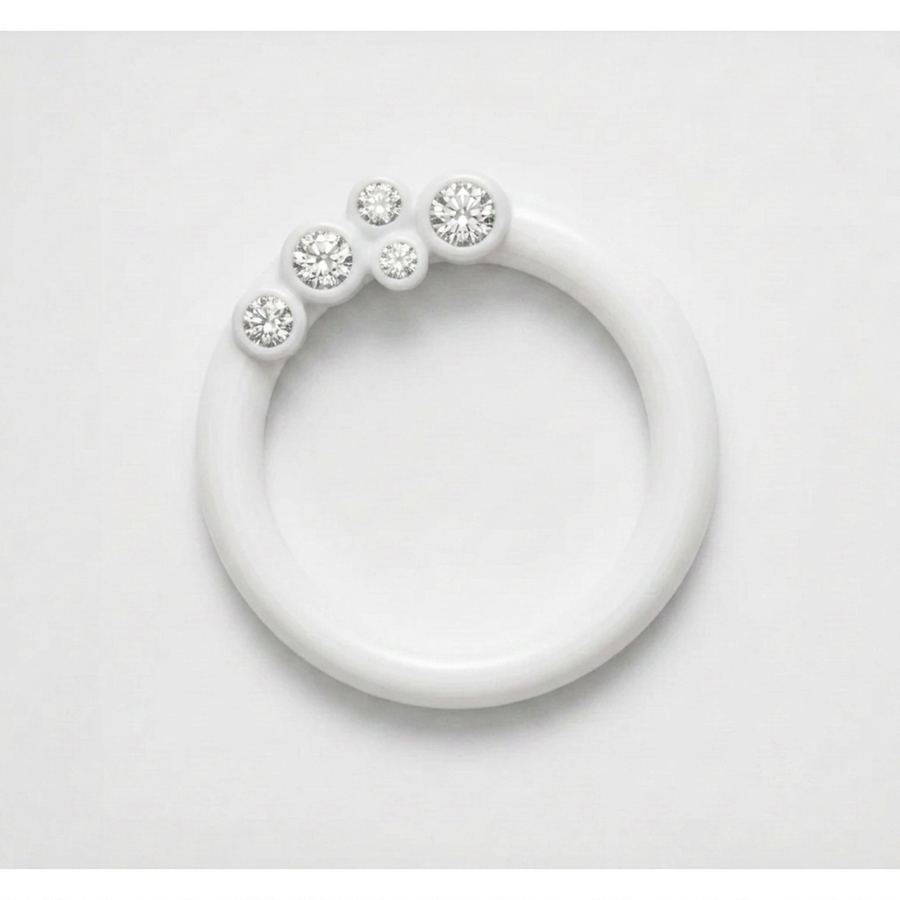 A minimalist white resin ring with five clear round-cut diamonds set along the upper arc, photographed on a clean white background.