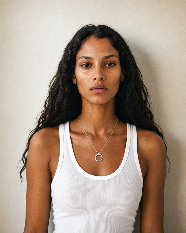A woman wearing a delicate silver necklace with a circular pendant, and lab-grown diamond detailing