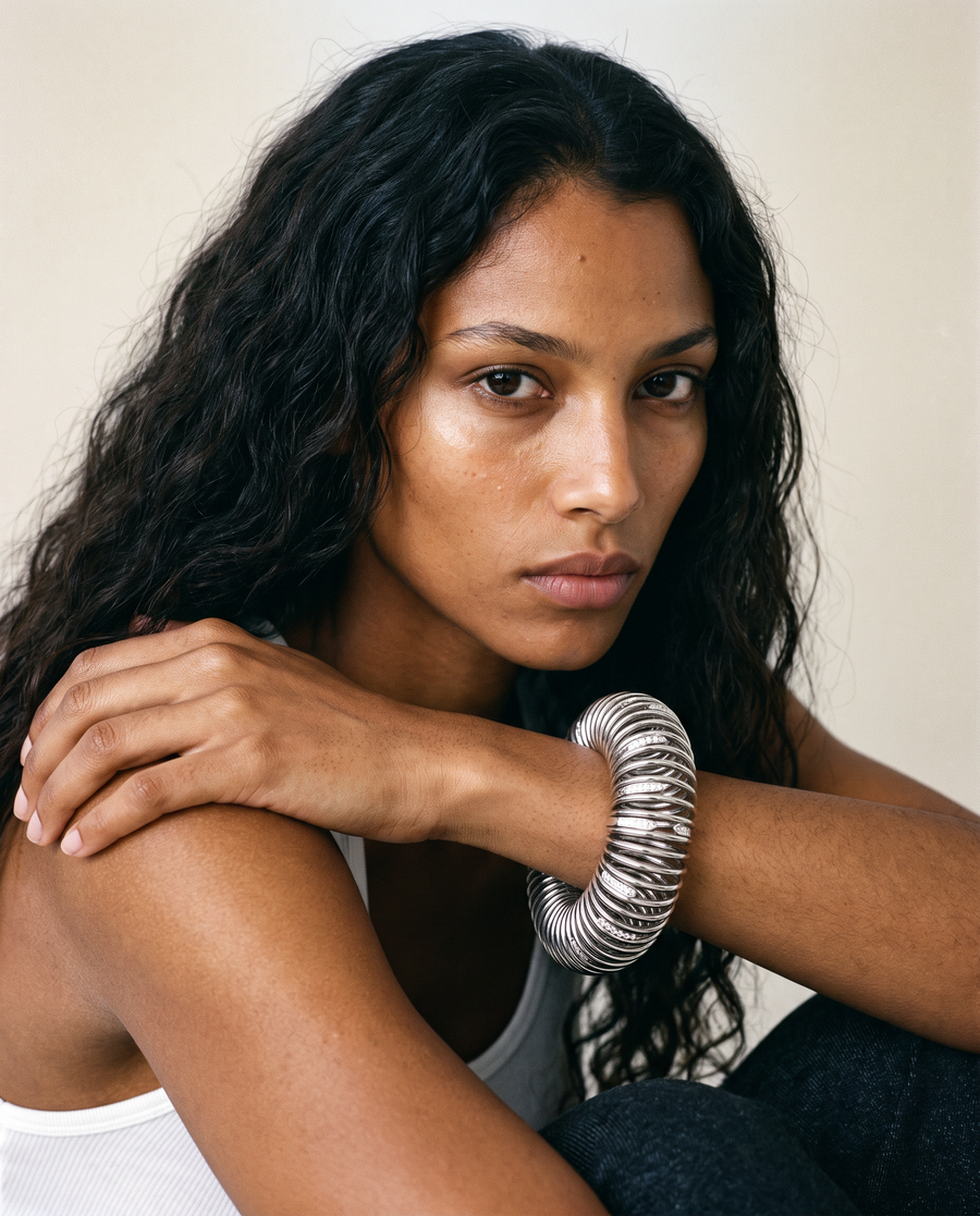 Model wearing a large, chunky silver coiled bangle on her wrist.