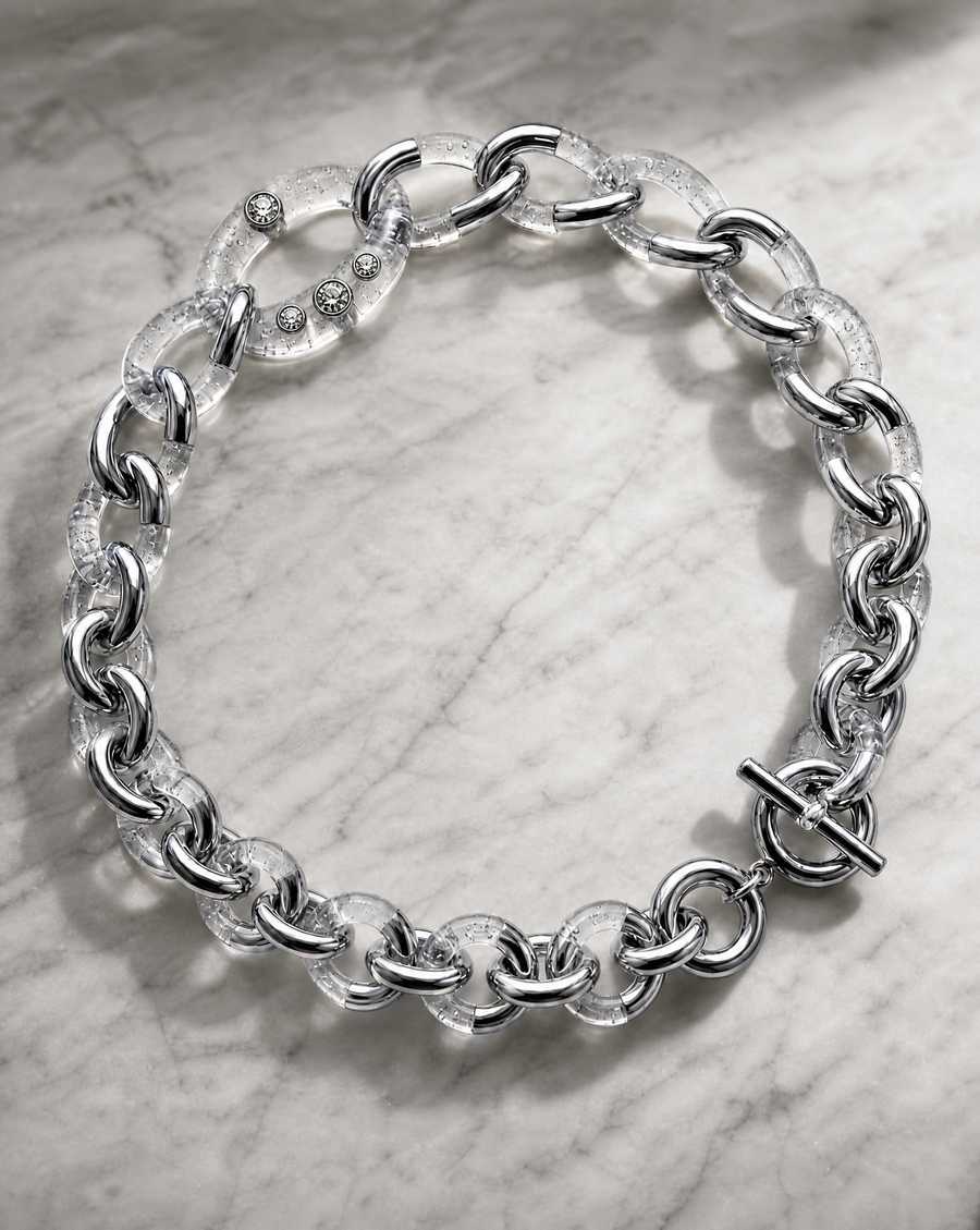 A chunky silver chain necklace with a toggle clasp, displayed on a light gray marble surface.