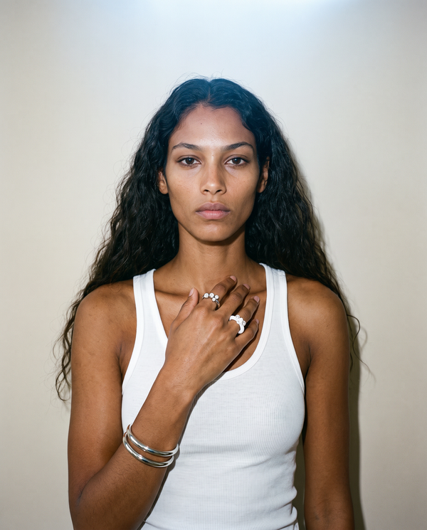 Model wearing silver bangles, and silver and white resin rings set with bezel diamonds 